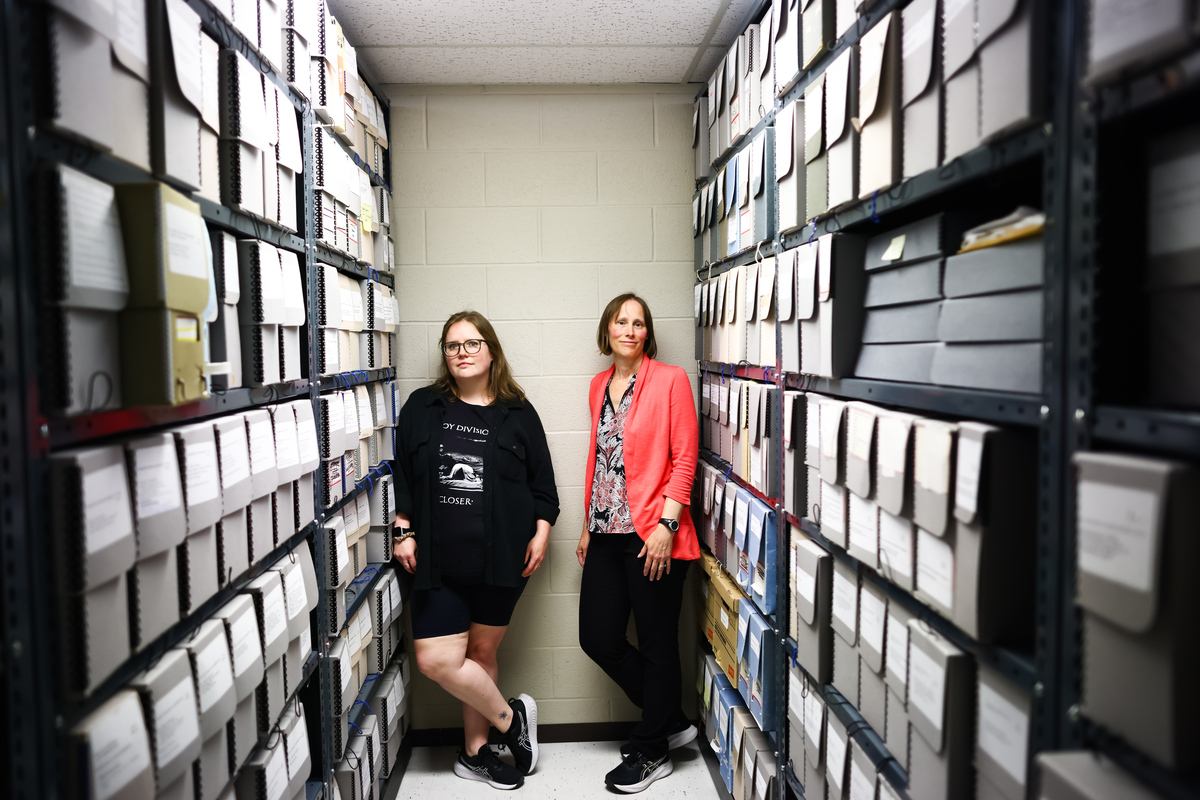 Claire Wilton, the archivist at the Anglican Diocese, right, and Sarah McDougall, the archives assistant, among the diocese's stacks in Toronto, Ontario, Canada on June 8, 2026. Six months after Canada expanded its citizenship eligibility, requests are flooding in for archival records. The documents are vital for proving ties to the country. (Cole Burston/The New York Times)