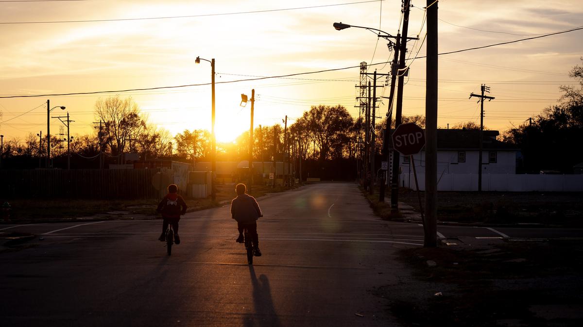 The sun sets on Brooklyn, Illinois, as two people bike through town on Nov. 24, 2024. (E. Jason Wambsgans/Chicago Tribune)