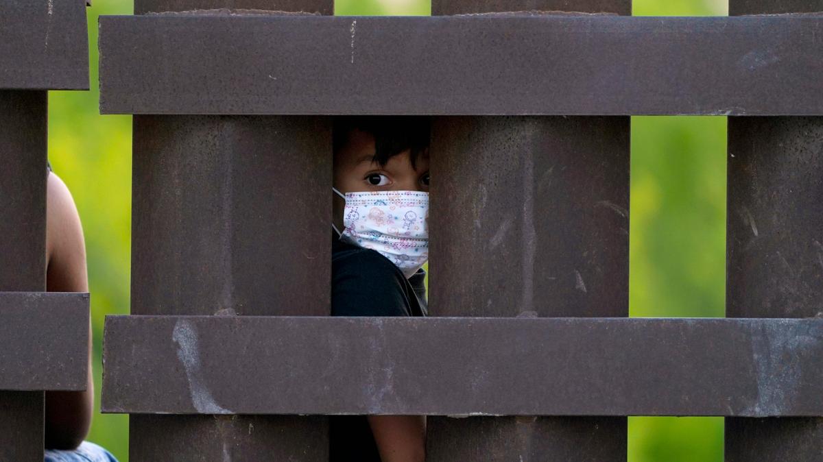 Un niño inmigrante mira a través del muro de metal que divide la frontera entre Estados Unidos y México, cerca del punto fronterizo en Abram-Perezville, en Texas, el 21 de marzo de 2021.