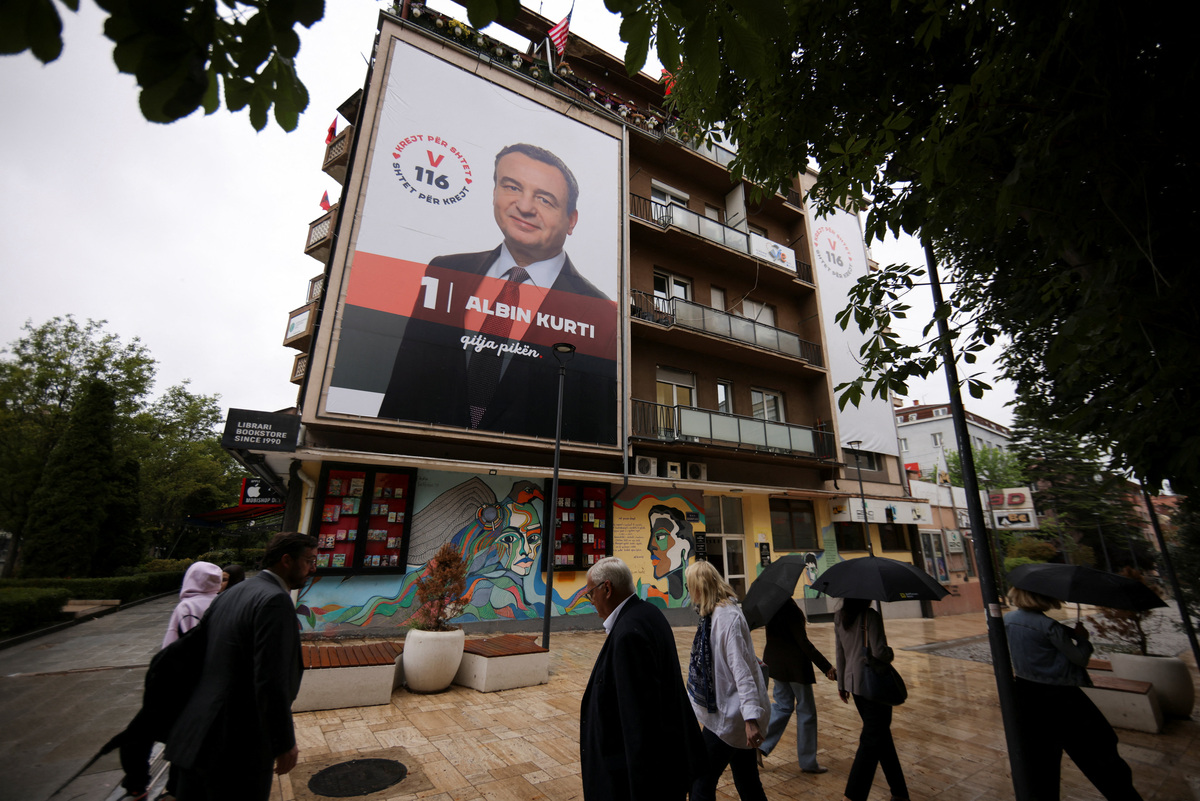 People walk near an election poster showing Prime Minister of Kosovo and Levizja Vetevendosje (Movement for Self-Determination) party leader Albin Kurti in Pristina, Kosovo, June 4, 2026. Kosovo is to hold a snap parliamentary election, the third in just over a year, after parliament failed to elect a new head of state. REUTERS/Valdrin Xhemaj