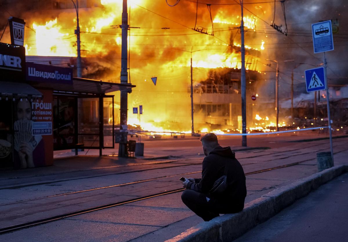 A resident watches a building burn after a Russian missile and drone strike in Kyiv, Ukraine, on Sunday. Moscow pounded Kyiv and surrounding areas with hundreds of drones and missiles on Sunday in one of the heaviest bombardments of the city since the start of the four-year war, firing an Oreshnik hypersonic missile near the capital.