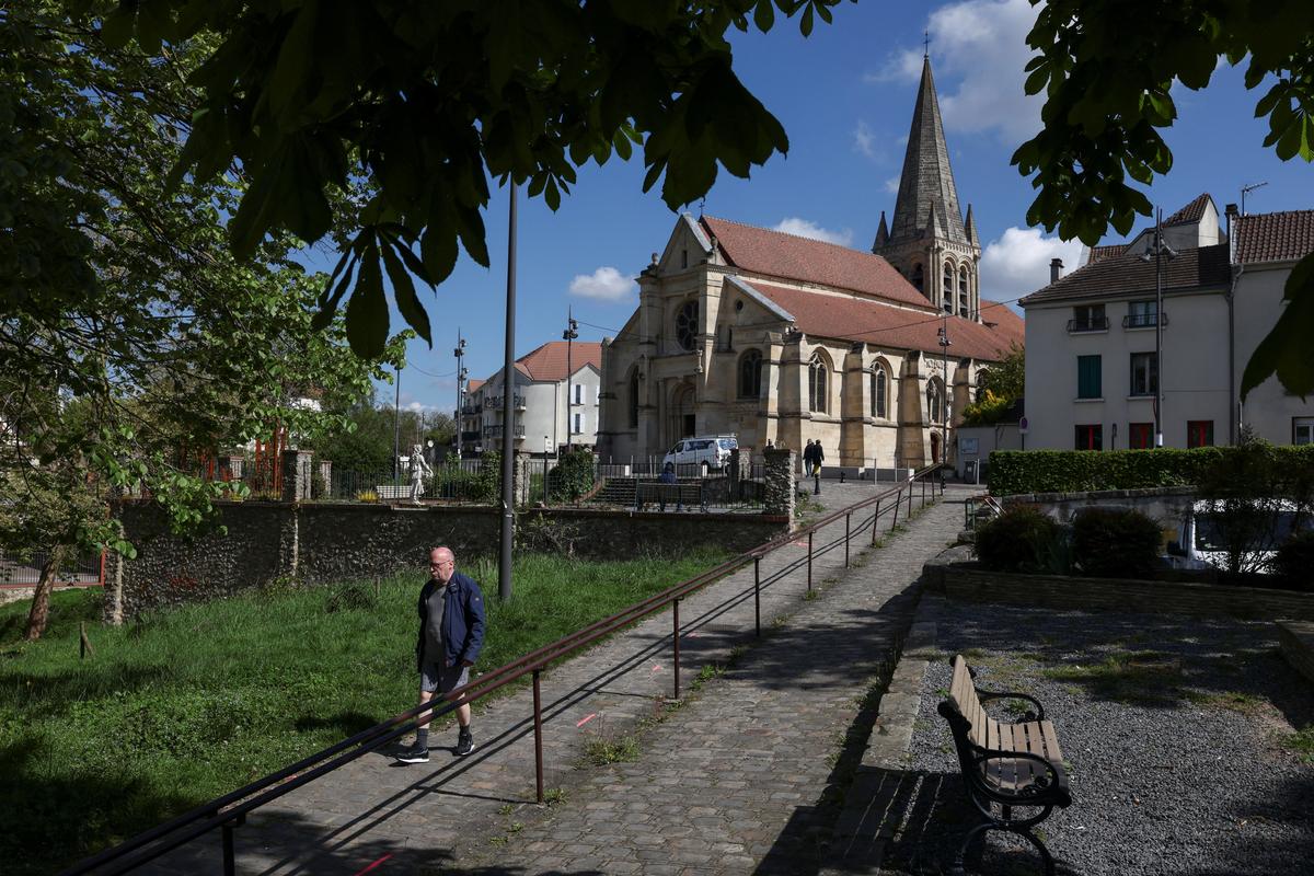A person walks through a park near a church in an area known as "Sarcelles-village" in the Paris suburb of Sarcelles, France, April 14, 2026. REUTERS/Tom Nicholson