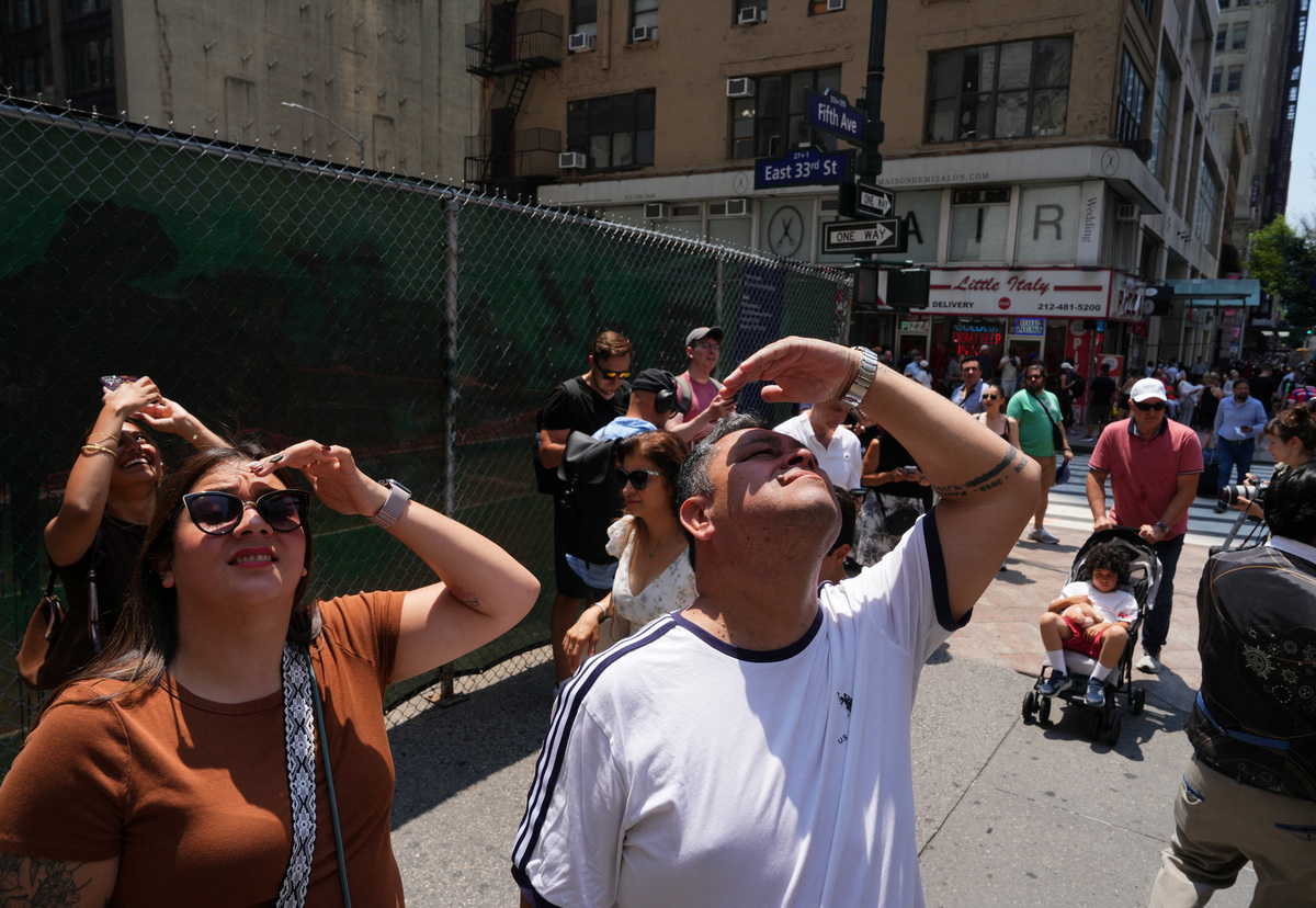 People look up at two people displaying a banner as they stage a protest atop the Empire State Building in the Manhattan borough of New York, U.S., July 1, 2026.  REUTERS/Adam Gray