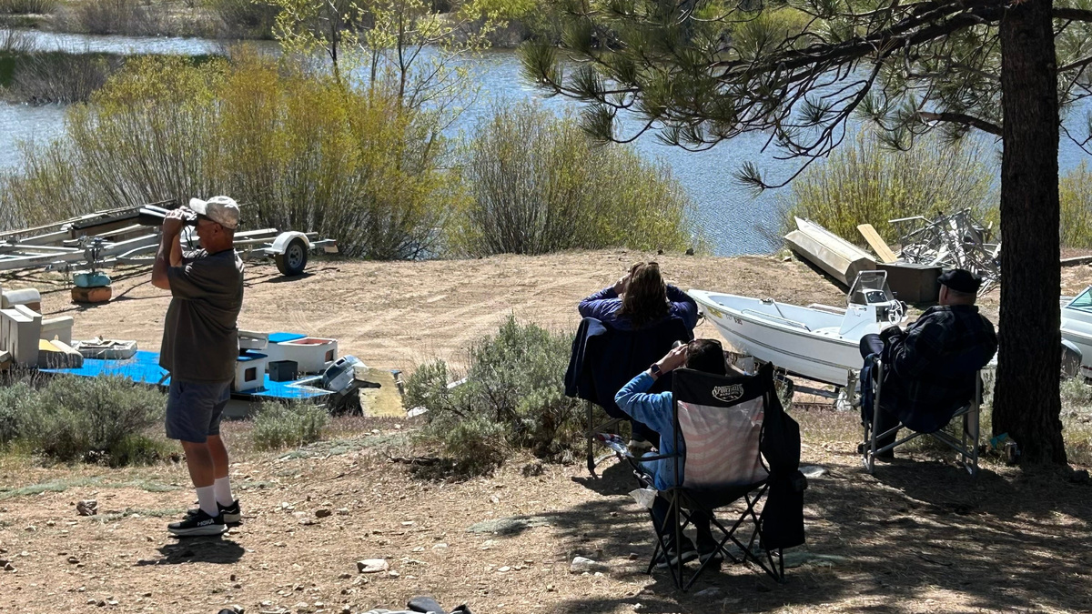 Fans of Jackie and Shadow, the famous bald eagles of Big Bear Lake, are pictured looking through binoculars, hoping for a chance to see the birds in person. To do so takes patience and an eagle eye.