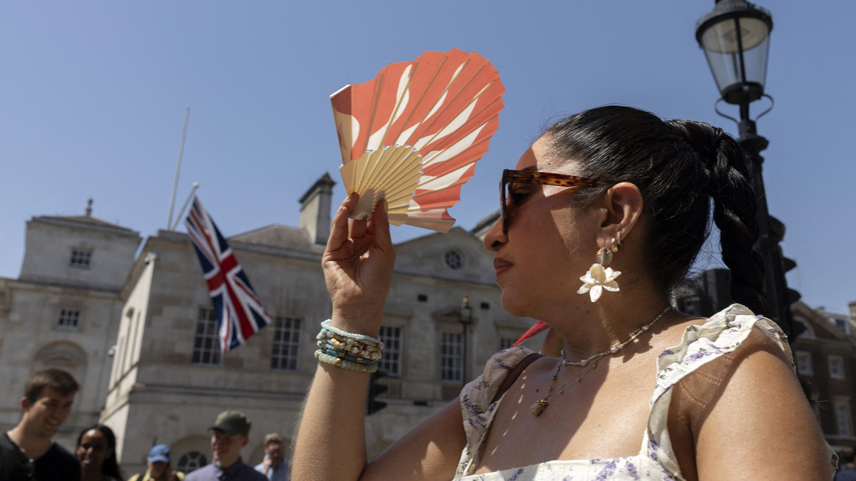 A person shields their face from the heat of the sun with a fan, in central London on June 25, 2026, during a heatwave. The UK recorded its hottest ever June temperature on June 24 with the mercury rising to 36.1C (97F) in southern England, breaking the previous record of 35.6C set in 1976. (Brook Mitchell/AFP/Getty Images/TNS)