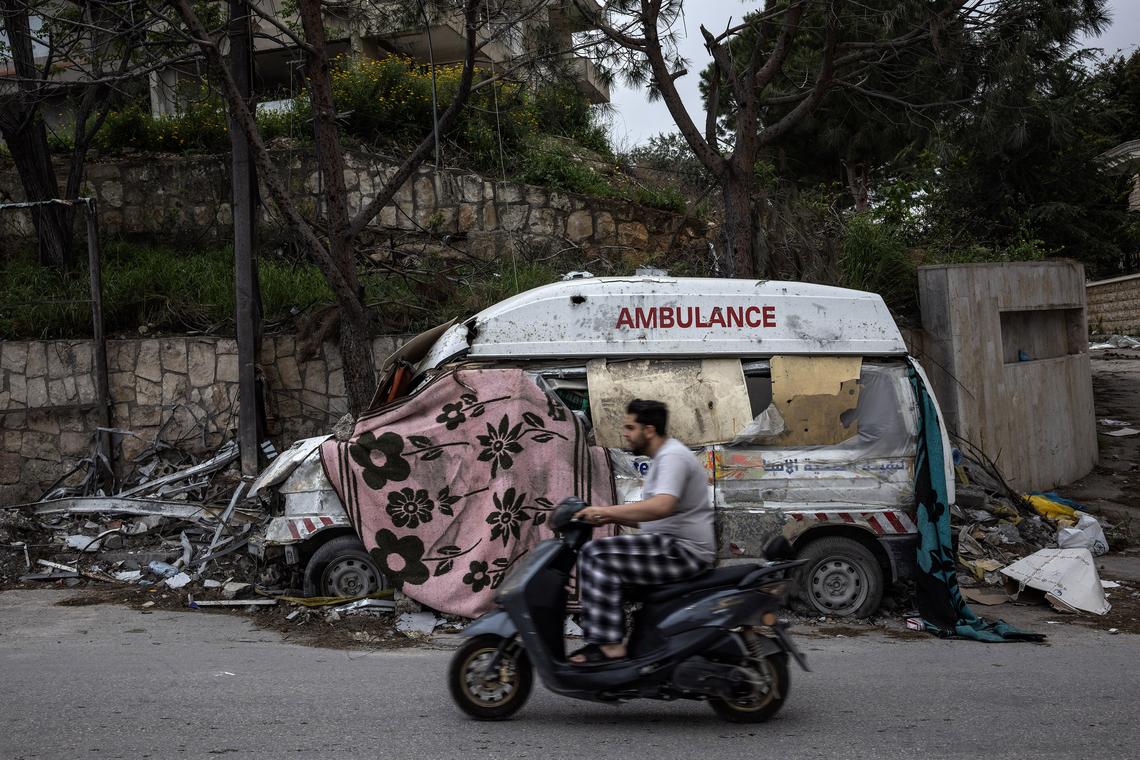 A man passes by a destroyed Lebanese ambulance in the southern village of Jouaiyya, Lebanon, as people return to their homes after the announcement of a 10-day ceasefire in the Israeli Hezbollah war, April 18, 2026. (David Guttenfelder/The New York Times)