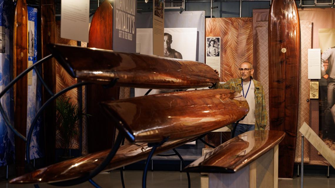 Tom Dahnke, longtime docent, touches one of the replica surfboards made by board shaper Bob Pearson, of Santa Cruz, at the California Surf Museum in Oceanside on Tuesday, April 21, 2026. These boards ranging from 11 feet to 16 feet, are a part of the museums new exhibit called Surfriding: Hawaiian Royaltys Gift to the World, which showcases how surfing was introduced throughout the world. (Kristian Carreon / The San Diego Union-Tribune)