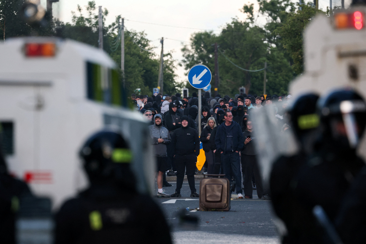 Anti-immigrant protesters stand behind a bin, as police block a road, following a knife attack on June 8, which left a man seriously injured and prompted police to declare a critical incident, in Belfast, Northern Ireland, June 10, 2026. REUTERS/Isabel Infantes