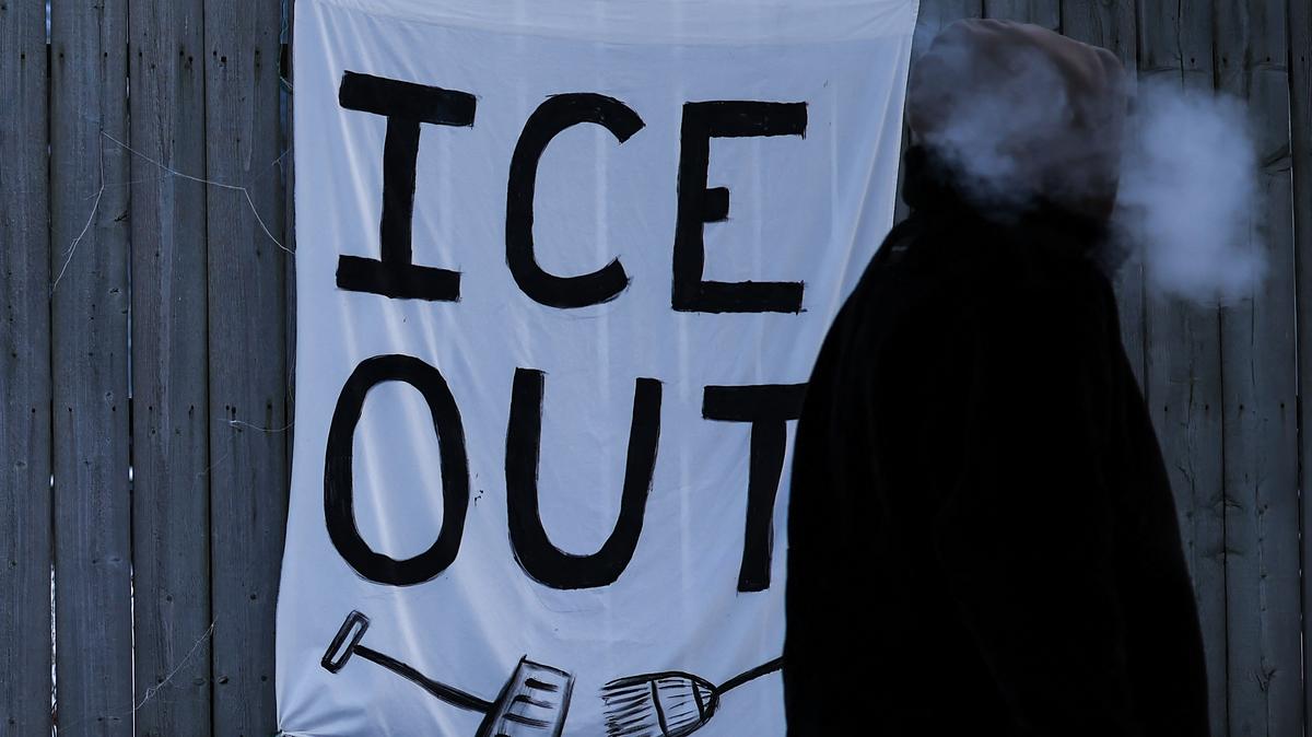 US-IMMIGRATION-ICE-SHOOTING. A man walks past a sign hanging on a fence in Minneapolis, Minnesota, on February 3, 2026. 