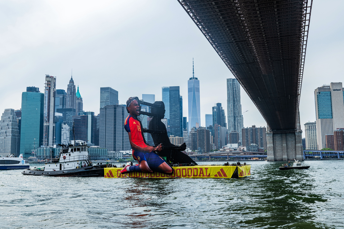 An Adidas barge, with an image of Spanish soccer player Lamine Yamal, floats on the East River during an Adidas Home of Soccer event in Brooklyn Bridge Park in New York on June 26, 2026. As World Cup matches take place across the United States, Nike and Adidas, the two largest sportswear companies in the world, are spending millions of dollars in a duel over the future of soccer in America. (Emma Rose Milligan/The New York Times)