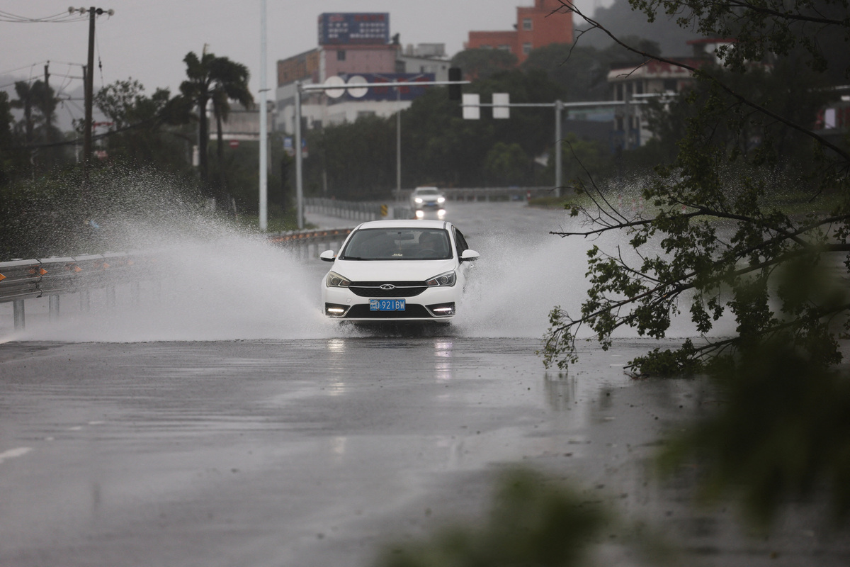A car drives past a fallen tree on a flooded road after heavy rain brought by Typhoon Bavi in Wenzhou, Zhejiang province, China, July 12, 2026. REUTERS/Go Nakamura