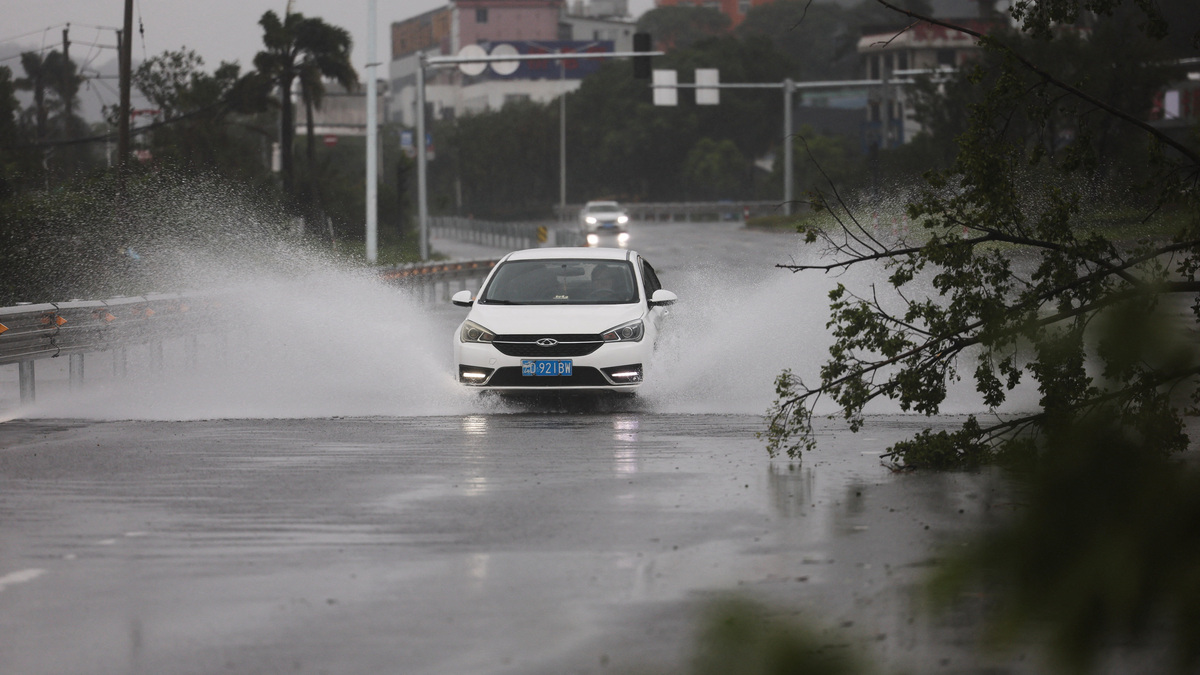 A car drives past a fallen tree on a flooded road after heavy rain brought by Typhoon Bavi in Wenzhou, Zhejiang province, China, July 12, 2026. REUTERS/Go Nakamura