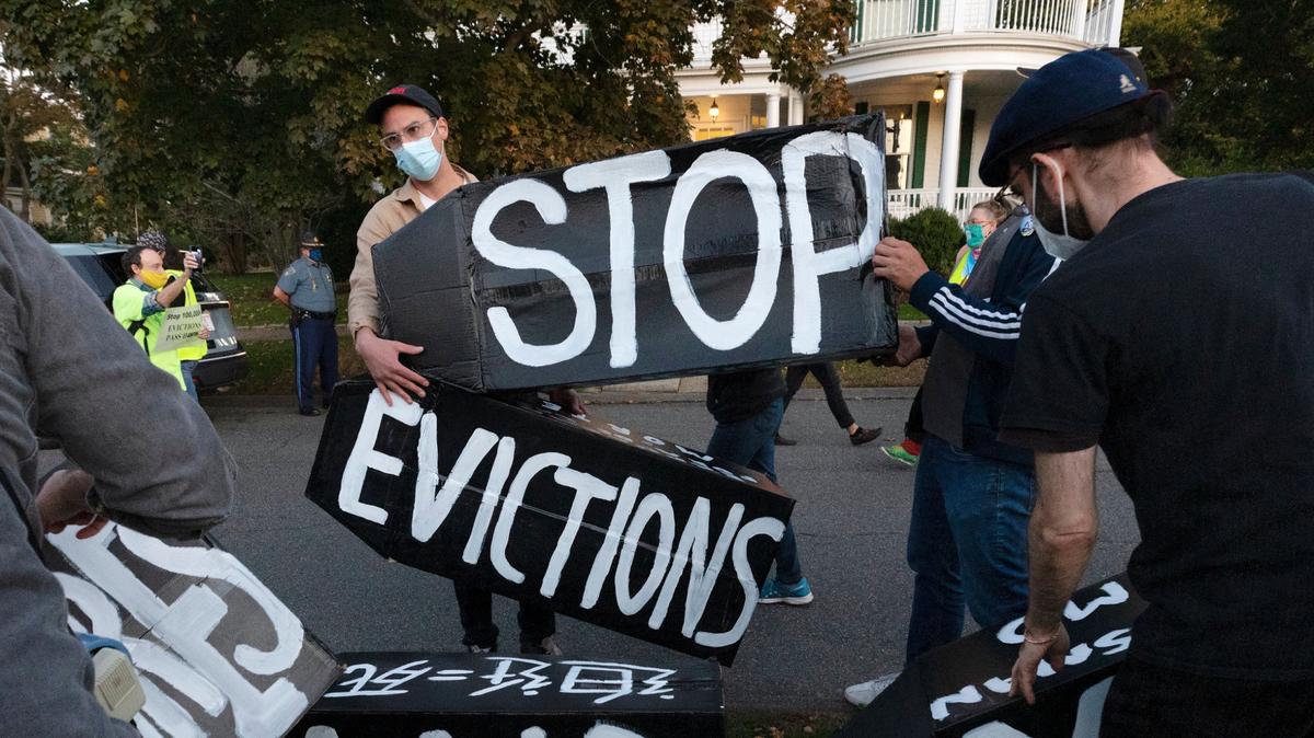 In this Oct. 14, 2020, file photo, housing activists erect a sign in front of Massachusetts Gov. Charlie Baker’s house in Swampscott, Mass.
