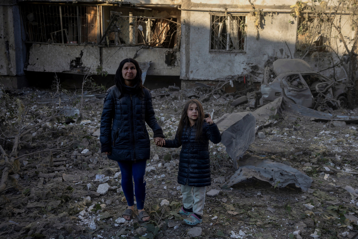Olha Mudra, 35, and her six-year-old daughter, Nataliia, stand in front of their damaged apartment building in Kyiv, covered in dust after surviving a nearby strike, amid Russia's attack on Ukraine, in Kyiv, Ukraine, June 2, 2026. REUTERS/Thomas Peter