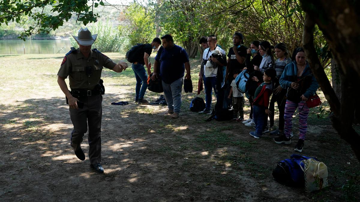 Agentes del Departamento de Seguridad Pública de Texas procesan a un grupo de inmigrantes que cruzó la frontera y se entregaron a las autoridades en Del Rio, Texas, el 16 de junio de 2021. El gobernador Greg Abbott aprobó la medida de que los agentes pueden detener los autos sospechosos de transportar inmigrantes por temor a que transmitan el COVID-19. La medida ha sido criticada duramente como racista.