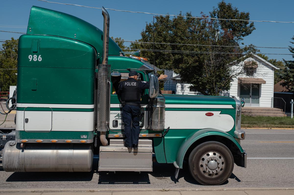 Joe Baez, a truck enforcement officer in Manhattan, Ill., pulls over a semi for being too long in a length-restricted stretch of road on Sept. 15, 2025. 25 years ago, the far outskirts of the Chicago suburbs were mostly farmland. Today, warehouse complexes dominate. With them, the roads have become increasingly dangerous. (Jamie Kelter Davis/The New York Times)..