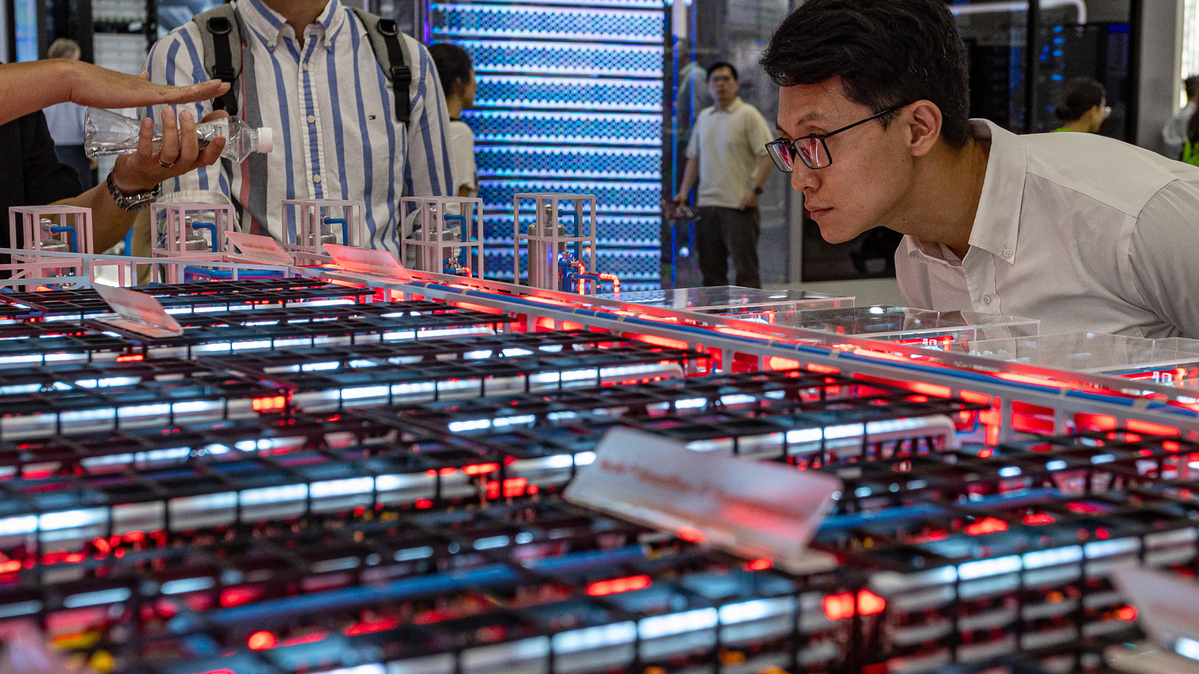 An attendee leans in to carefully examine the modular grid layout and server configurations of a large data center hardware model on June 3, 2026, in Taipei, Taiwan. Running June 2–5 across four venues in Taipei's Nangang and Xinyi districts under the theme "AI Together," the annual trade show has drawn more than 1,500 exhibitors and industry heavyweights including NVIDIA CEO Jensen Huang to showcase next-generation AI chips, robotics, and computing infrastructure, cementing Taiwan's role as the world's pre-eminent hub for semiconductor and AI supply chain innovation. (Cheng Chia Huang/Getty Images/TNS)