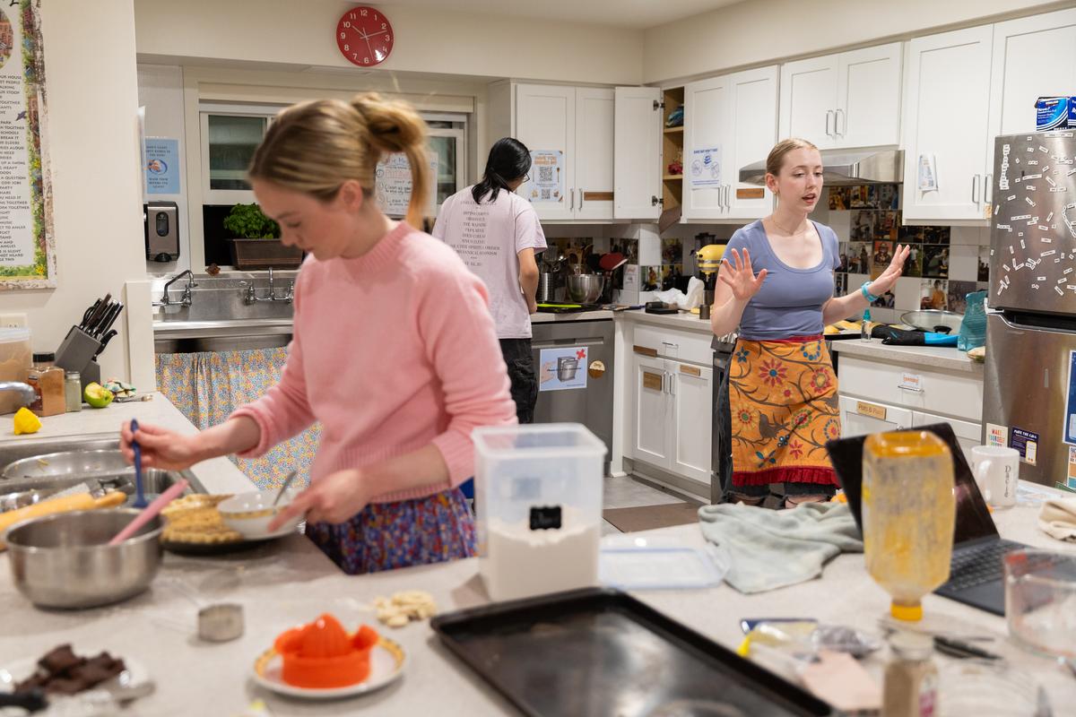 Seraphina Shutt, left, puts finishing touches on her great-grandmother's shredded apple pie while Meghan Howard, right, waits on lavender scones in the oven at the Dacie Moses House, Carleton College's cookie house in Northfield, Minn., March 30, 2026. For decades, Carleton College has kept a place where students and others can come, bake and share. (Liam James Doyle/The New York Times)