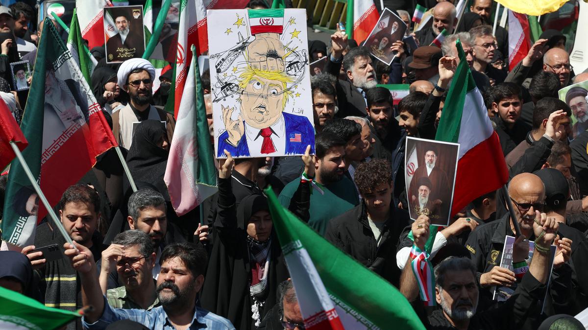A woman holds a poster mocking U.S. President Donald Trump while others hold portraits of Iran's slain supreme leader Ayatollah Ali Khamenei and his son and successor Mojtaba Khamenei during a rally to commemorate his death in Tehran, Iran, on Thursday, April 9, 2026. (-/AFP/Getty Images/TNS)