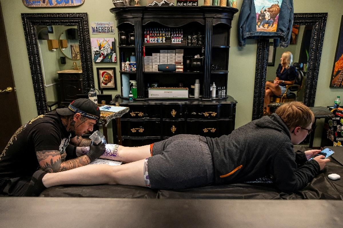 Randolph Torres tattoos the leg of Lexya Siebrands as Lexya's mother Jyl Siebrands watches in Fort Morgan, Colorado, U.S., May 11, 2026.  REUTERS/Kevin Mohatt