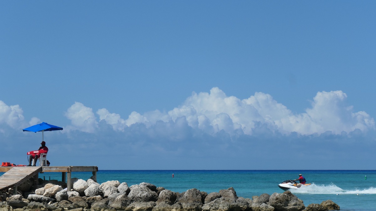 Jet skiing is a popular water sport along the beaches of the Grand Bahama Islands. As seen here, on May 9, 2019, a lifeguard keeps a watchful eye from a rock jetty as a jet skier passes by. 