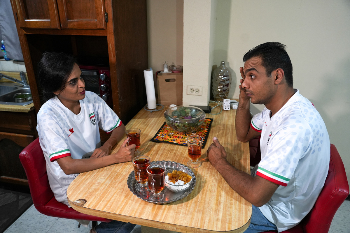 An Iranian couple, Maryam Asadi and Sadegh Galavi, chat while wearing jerseys of Iran’s national soccer team at their home in Tijuana, where a small Iranian community reflects broader political divisions within the diaspora ahead of the team’s World Cup campaign, in Tijuana, Mexico, June 10, 2026. REUTERS/Aimee Melo