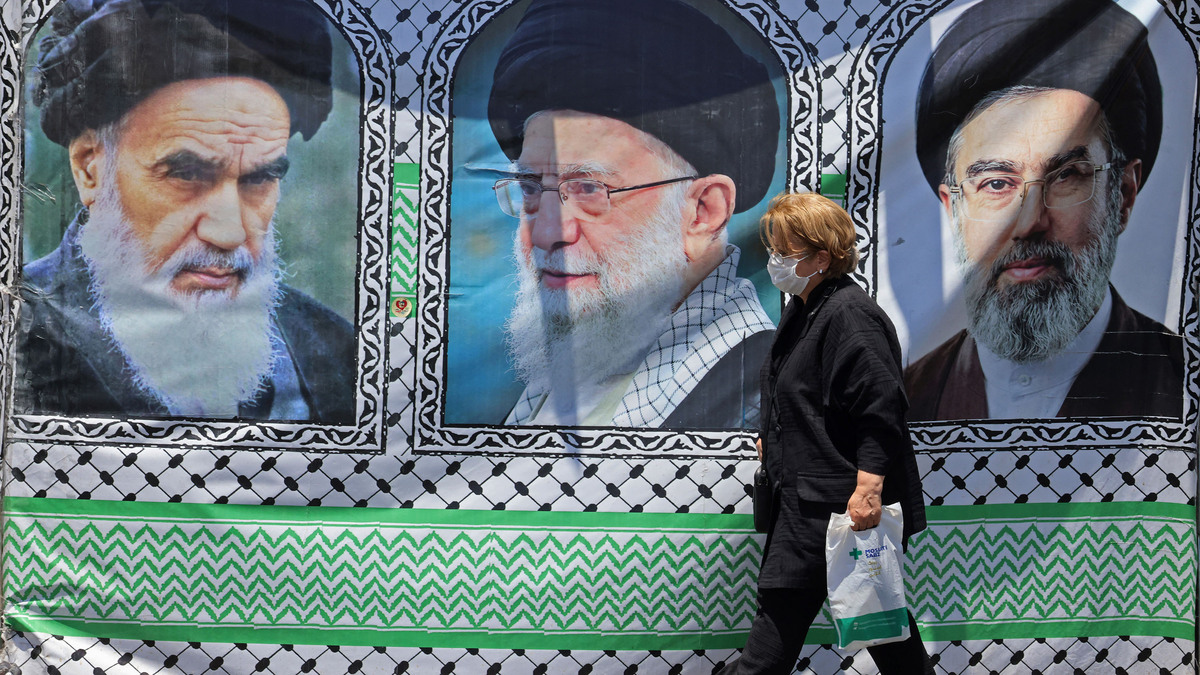 A woman walks past a banner bearing the images of the late founder of the Islamic Revolution supreme leader Ayatollah Ruhollah Khomeini, left, the late Iranian supreme leader Ali Khamenei and his son, the current supreme leader Mojtaba Khamenei, right, erected along a street at the Vanak Square in Tehran on June 10, 2026. Iran's foreign ministry said on June 10 that the United States had damaged the ongoing international diplomatic effort to end the war, after more U.S. strikes on targets in southern Iran. (Atta Kenare/AFP/Getty Images/TNS)