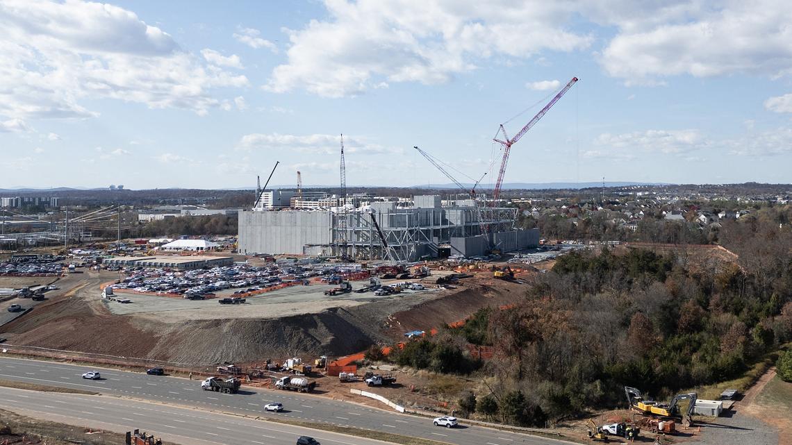 An aerial view shows cars passing a data center under construction in Ashburn, Virginia on Nov. 12, 2025. Data centers are the physical infrastructure that make our digital lives possible, yet most people have never seen one up close or understand how they operate. Roughly 12,000 data centers are in operation in the world, with about half in the U.S., according to Cloudscene, a data center directory. (Andrew Caballero-Reynolds/AFP/Getty Images/TNS)