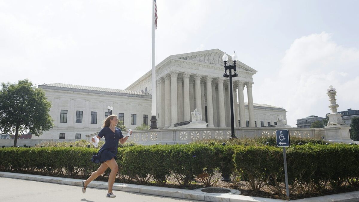 A news reporter carrying printed justice opinion announcements sprints outside U.S. Supreme Court on June 29, 2026, in Washington, DC. 