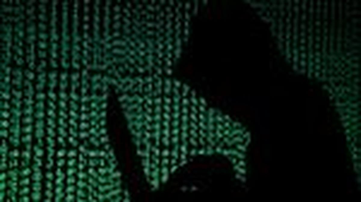 FILE PHOTO: A hooded man holds a laptop computer as cyber code is projected on him in this illustration picture taken on May 13, 2017. REUTERS/Kacper Pempel/Illustration/File Photo