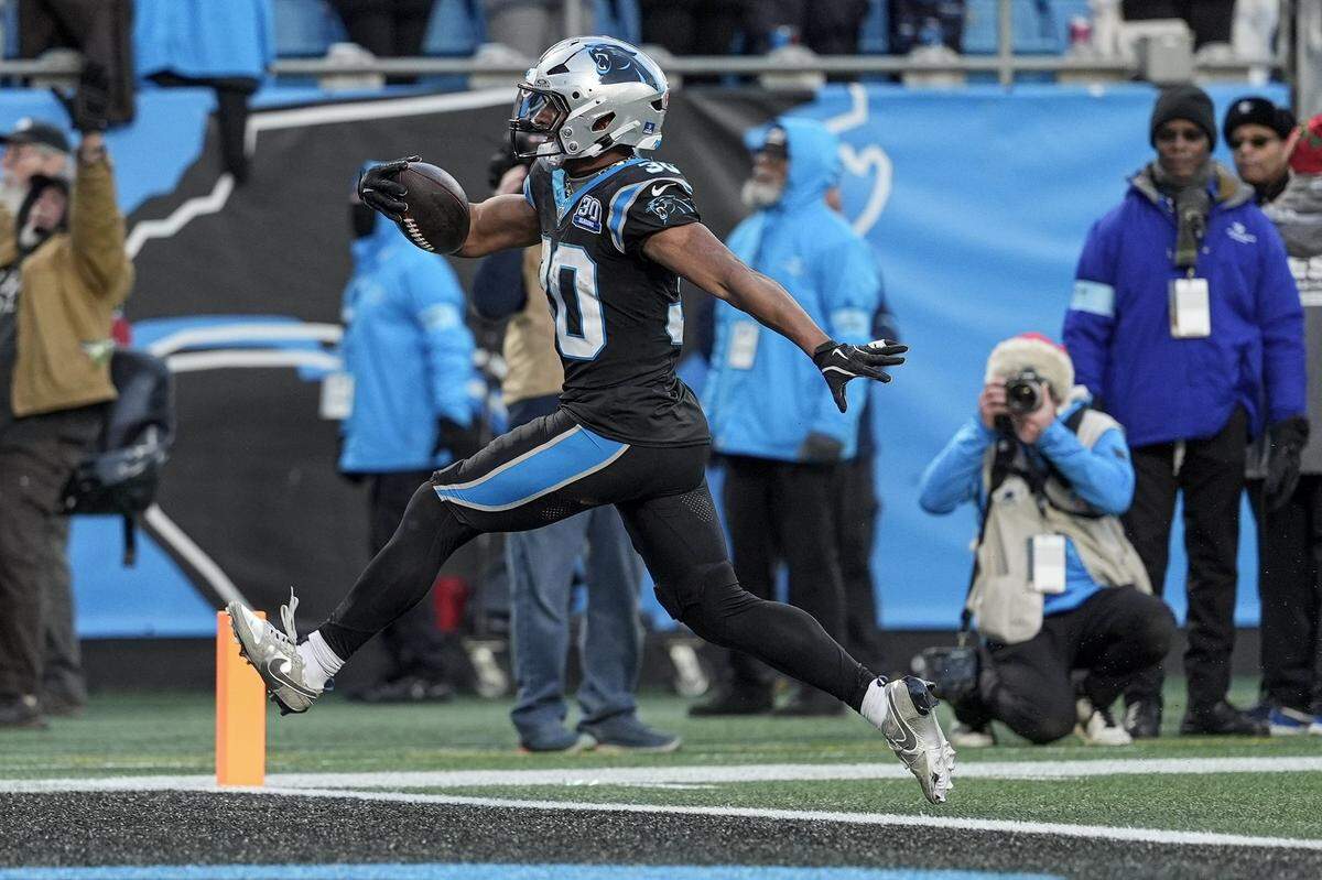 Dec 22, 2024; Charlotte, North Carolina, USA; Carolina Panthers running back Chuba Hubbard (30) scores in overtime to win the game during the second half at Bank of America Stadium.
