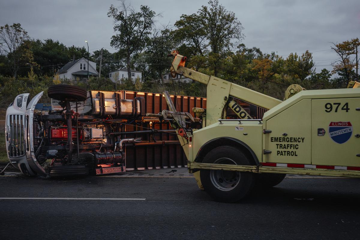 A rolled over semi sits on the side of Interstate 57 during morning rush hour in Riverdale, Ill., outside Chicago, on Oct. 22, 2025.25 years ago, the far outskirts of the Chicago suburbs were mostly farmland. Today, warehouse complexes dominate. With them, the roads have become increasingly dangerous. (Jamie Kelter Davis/The New York Times)....