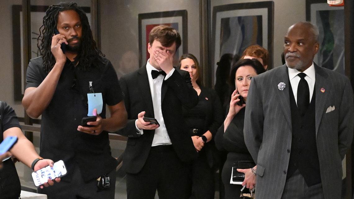 Attendees check their phones in the lobby of the Washington Hilton after shots were heard during the White House Correspondents' Dinner in Washington, D.C., on April 25, 2026. Shots were fired as US President Donald Trump attended a press dinner in Washington on April 25 night, witnesses and AFP reporters confirmed. Loud bangs were heard and guests at the black-tie White House Correspondents' Dinner scrambled to hide under tables. Tactical teams with guns drawn took position on the stage where Trump had been sitting before he was evacuated. (Alex Wroblewski/AFP via Getty Images/TNS)