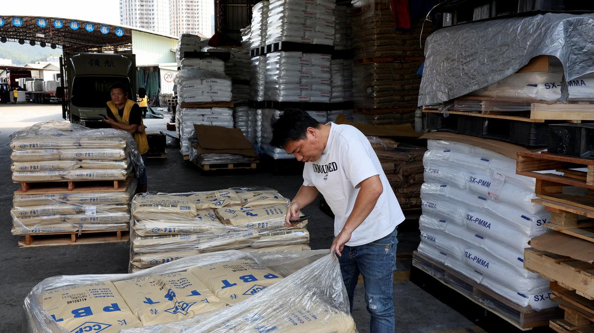 A worker takes a photo of bags of plastic pellets at a warehouse, as rising oil prices drive up production costs for plastic manufacturers, in Dongguan, Guangdong province, China, April 1, 2026.  REUTERS/Go Nakamura