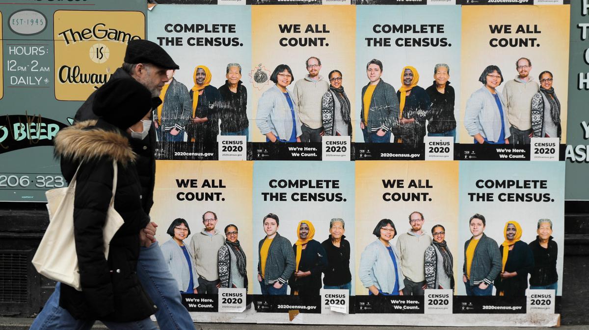 Una pareja camina frente a afiches que promueven la importancia de participar en el Censo 2020, el miércoles 1 de abril de 2020 en el vecindario Capitol Hill de Seattle.