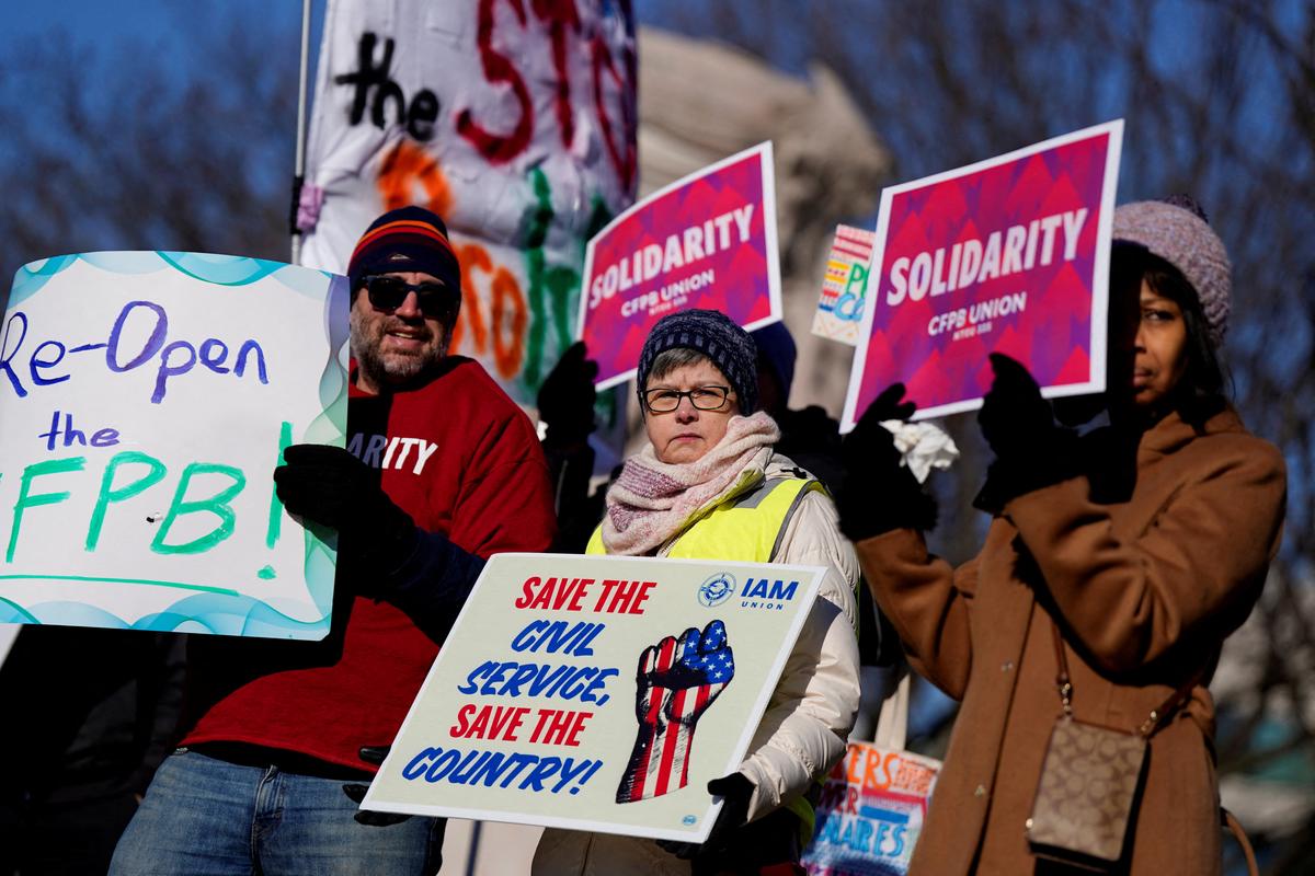 FILE PHOTO: Consumer Financial Protection Bureau (CFPB) workers hold placards as they rally on the day of a hearing in a case on the Trump administration's mass firings of CFPB workers, outside the U.S. District Court in Washington, D.C., U.S., March 3, 2025. REUTERS/Kent Nishimura/File Photo
