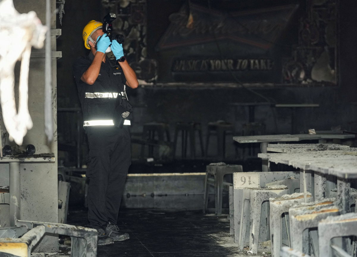 A forensic police official takes photographs the site of a deadly fire at a pub in Bangkok, Thailand, July 13, 2026. REUTERS/Arnun Chonmahatrakool