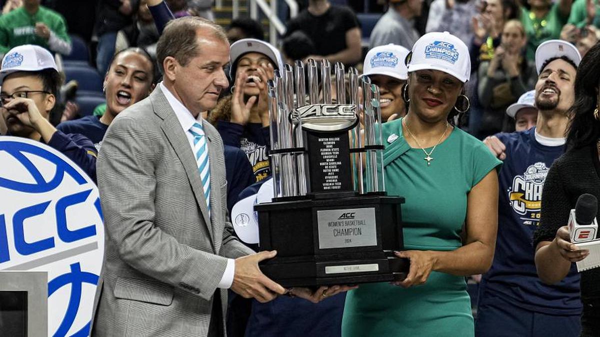  Mar 10, 2024; Greensboro, NC, USA; Commissioner of the ACC Jim Phillips (left) hands the champions trophy to Notre Dame Fighting Irish head coach Niele Ivey after defeating the NC State Wolfpack at Greensboro Coliseum. | David Yeazell-Imagn Images 