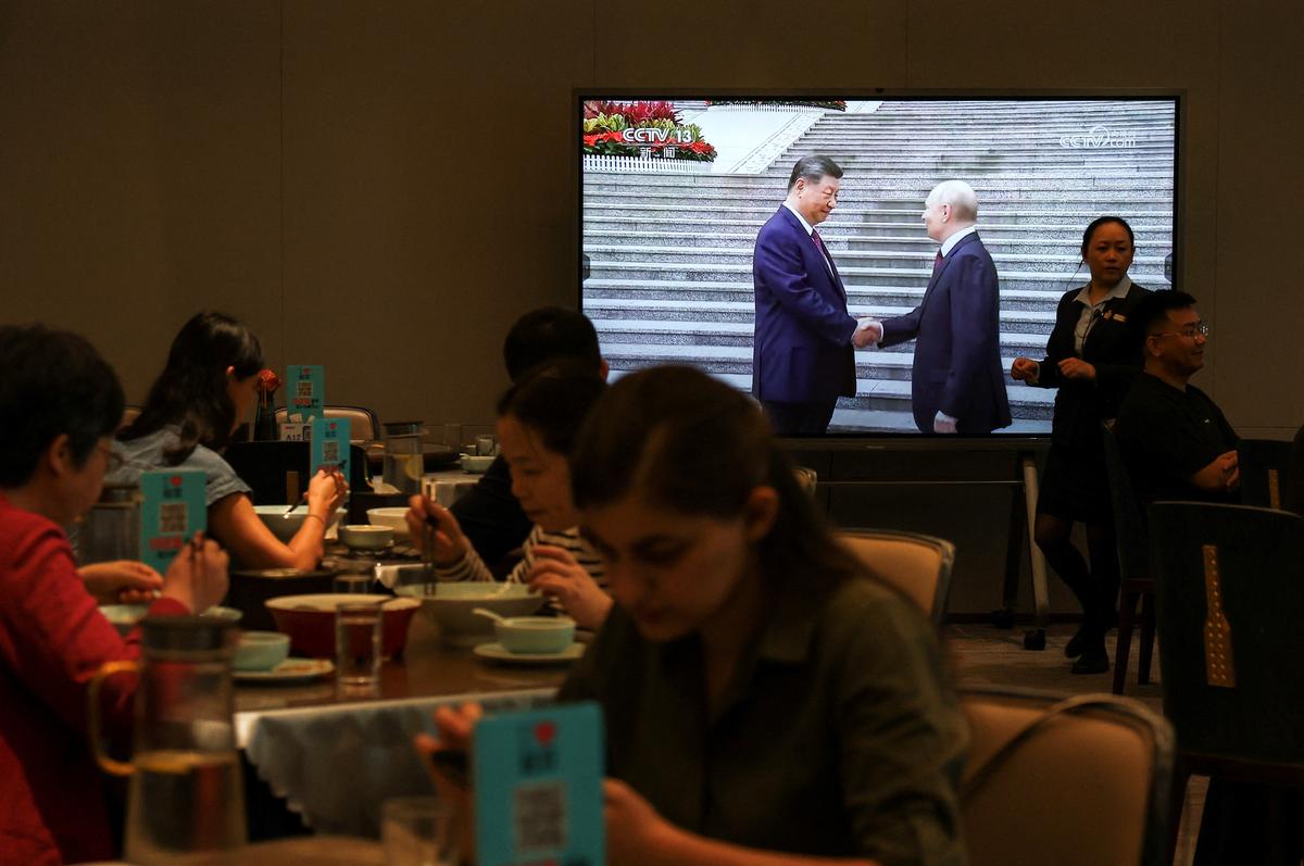 Customers dine near a screen showing a news footage of Chinese President Xi Jinping meeting Russian President Vladimir Putin at the Great Hall of the People, at a restaurant in Beijing, China May 20, 2026. REUTERS/Tingshu Wang