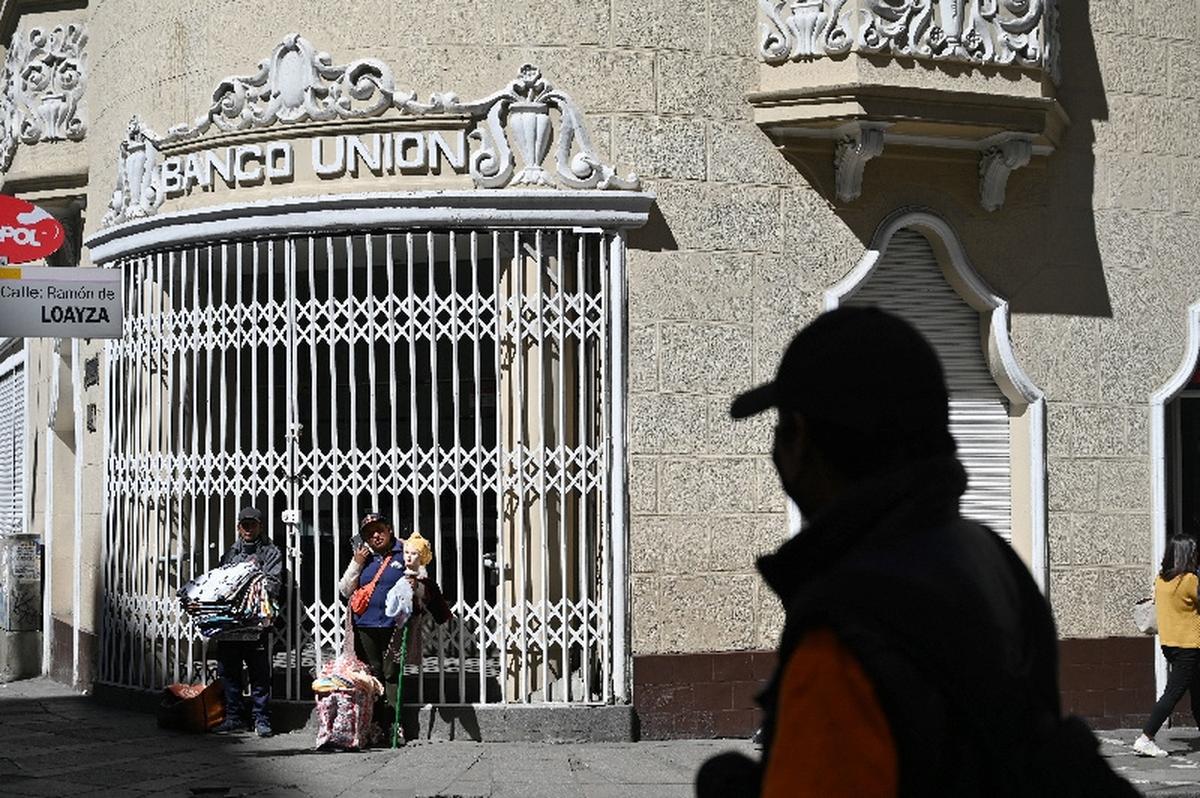 Vendors stand outside of a closed branch of the Banco Union bank, as several Bolivian banks temporarily closed branches due to ongoing unrest driven by anti-government demonstrations, in La Paz, Bolivia, May 19, 2026. REUTERS/Claudia Morales