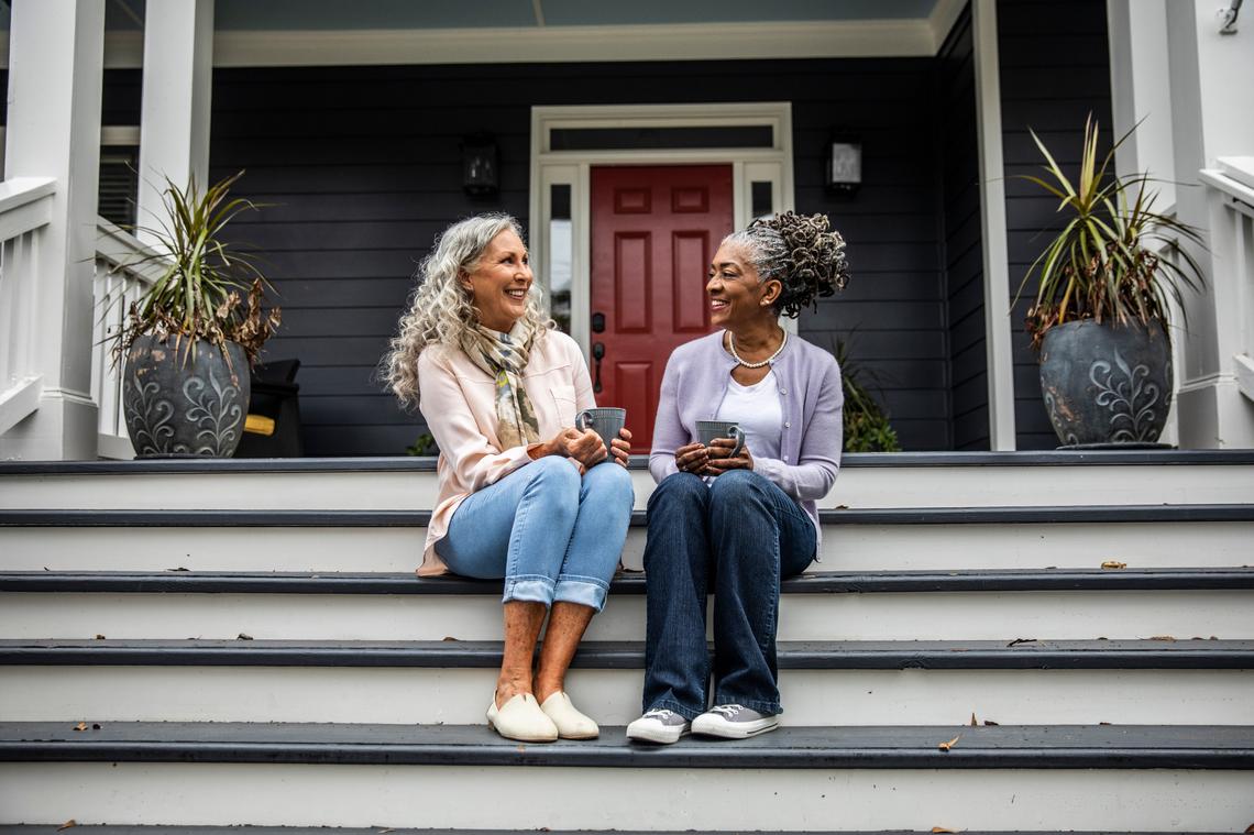 Senior women having coffee in front of suburban home.