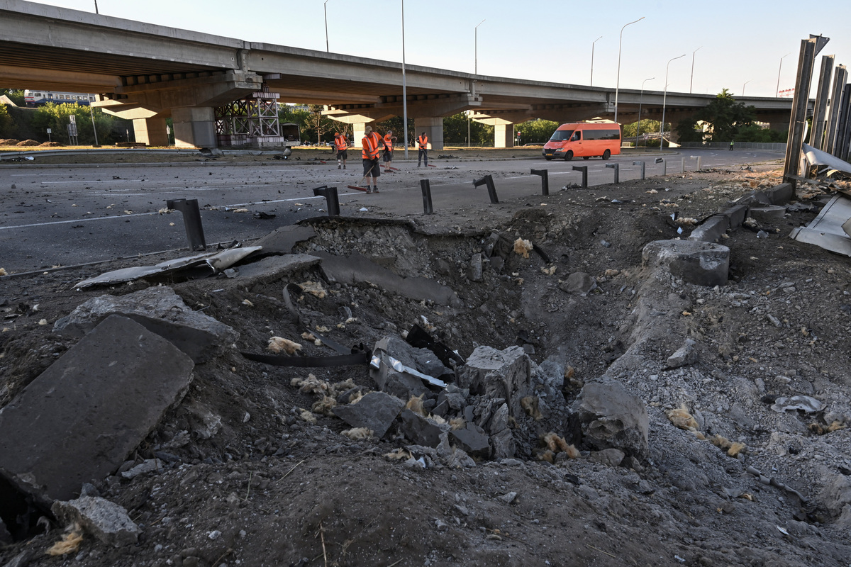 Municipal workers remove debris next to a hole in the ground that appeared after a Russian airstrike, amid Russia's attack on Ukraine, in Zaporizhzhia, Ukraine, June 20, 2026. REUTERS/Stringer