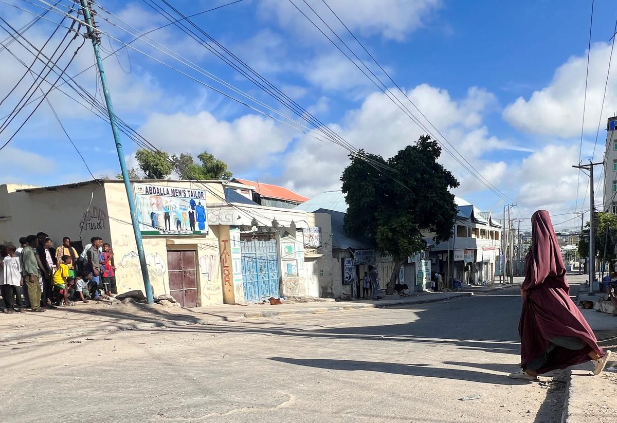 A woman walks across a deserted street as people peer to watch ahead of a protest against Somalia's President Hassan Sheikh Mohamud, where opposition leaders say his term ended in mid-May, while the president and his allies say he is allowed to stay on for a year until elections are held, in Mogadishu, Somalia June 4, 2026. Picture taken with a mobile phone. REUTERS/Feisal Omar