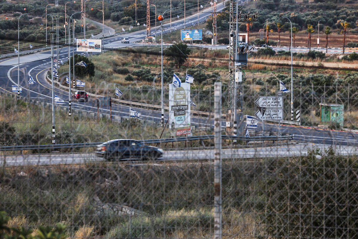 The road between Sinjil and Turmas Ayya, seen through the tall metal fencing installed by the Israeli military that closed off four of the five entrances to Sinjil, near Ramallah, in the Israeli-occupied West Bank, June 26, 2026. REUTERS/Ammar Awad