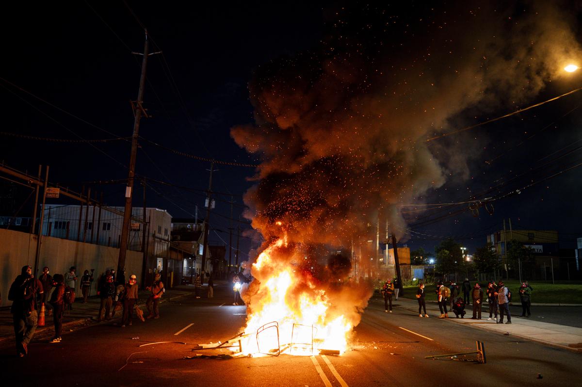 Demonstrators set debris on fire outside the Delaney Hall immigration detention center in Newark, N.J., May 30, 2026. Mayor Ras Baraka of Newark imposed a curfew early Sunday around the immigration detention center after a second consecutive night of unrest over living conditions there. (Vincent Alban/The New York Times)