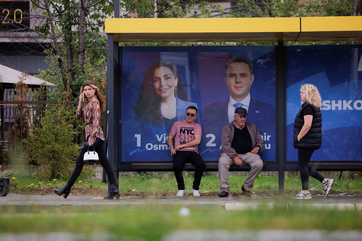 People wait at a bus station near the election posters of the Democratic League of Kosovo (LDK) party in Pristina, Kosovo, June 4, 2026. Kosovo is to hold a snap parliamentary election, the third in just over a year, after parliament failed to elect a new head of state. REUTERS/Valdrin Xhemaj