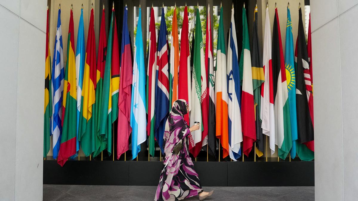 FILE PHOTO: A woman walks by a long row of flags at the IMF building during the 2026 annual IMF/World Bank Spring Meetings in Washington, D.C., U.S., April 16, 2026. REUTERS/Ken Cedeno/File Photo