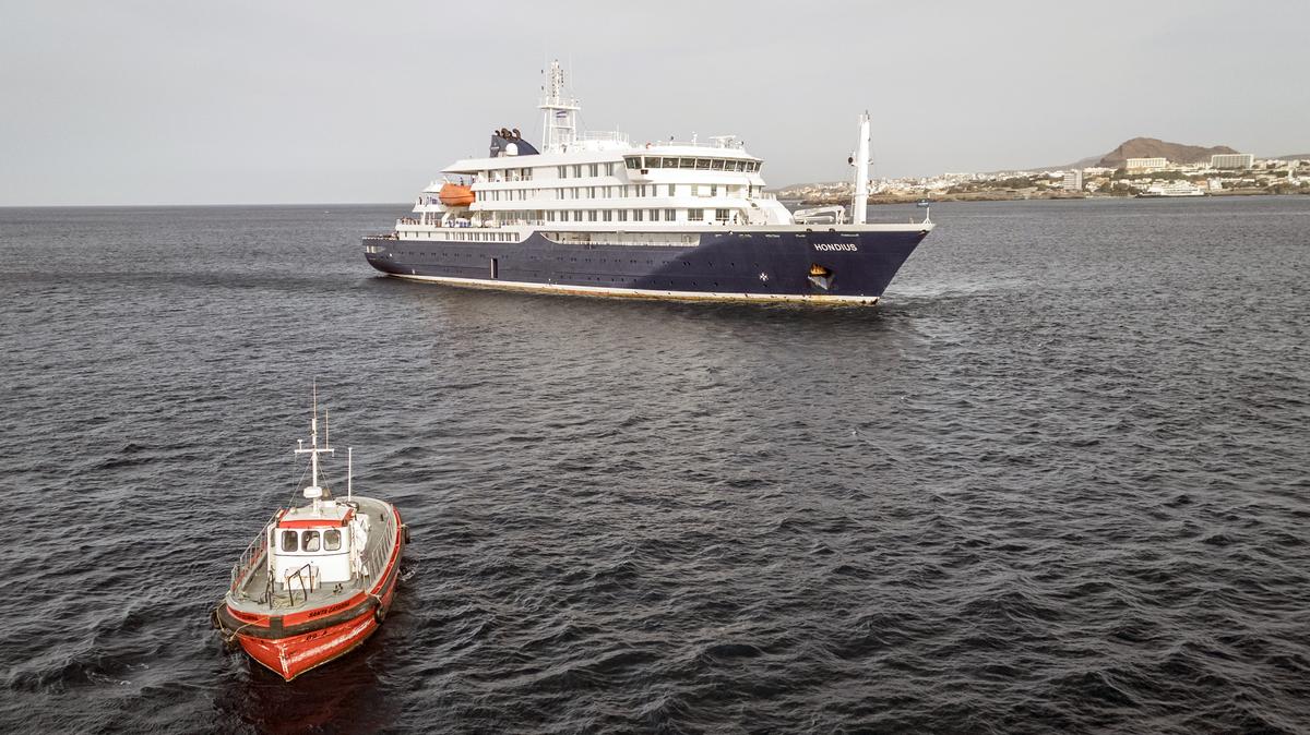 This aerial view shows a boat heading towards the port from the cruise ship MV Hondius, stationary off the port of Praia, the capital of Cape Verde, on May 6, 2026. Evacuations were taking place on May 6, 2026 from a cruise ship stricken with a deadly outbreak of hantavirus, the World Health Organization said, as experts confirmed a rare strain that can be transmitted between humans. Three people, two crew members and one other person, thought to be infected with the virus were being taken off the MV Hondius, anchored off Cape Verde, the WHO said. (AFP/Getty Images/TNS)