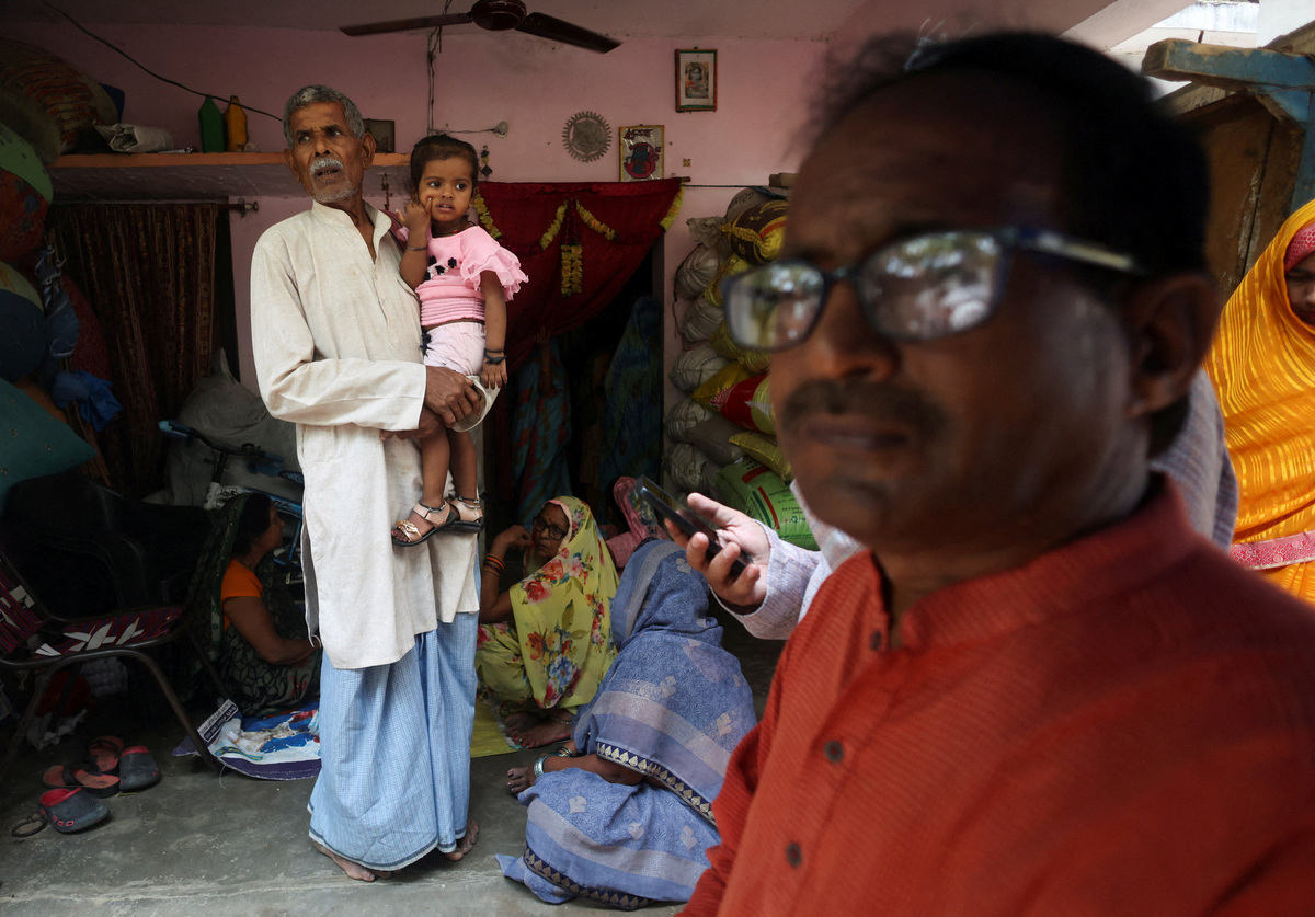 A man carries the daughter of Shivanand Chaurasia, an Indian seafarer aboard the Palau-flagged tanker MT Settebello who was among three crew members killed in one of the U.S. attacks on Indian-crewed tankers this week amid a blockade of Iran-related shipping, as people gather outside his house in Deoria, Uttar Pradesh, India, June 12, 2026. REUTERS/Priyanshu Singh