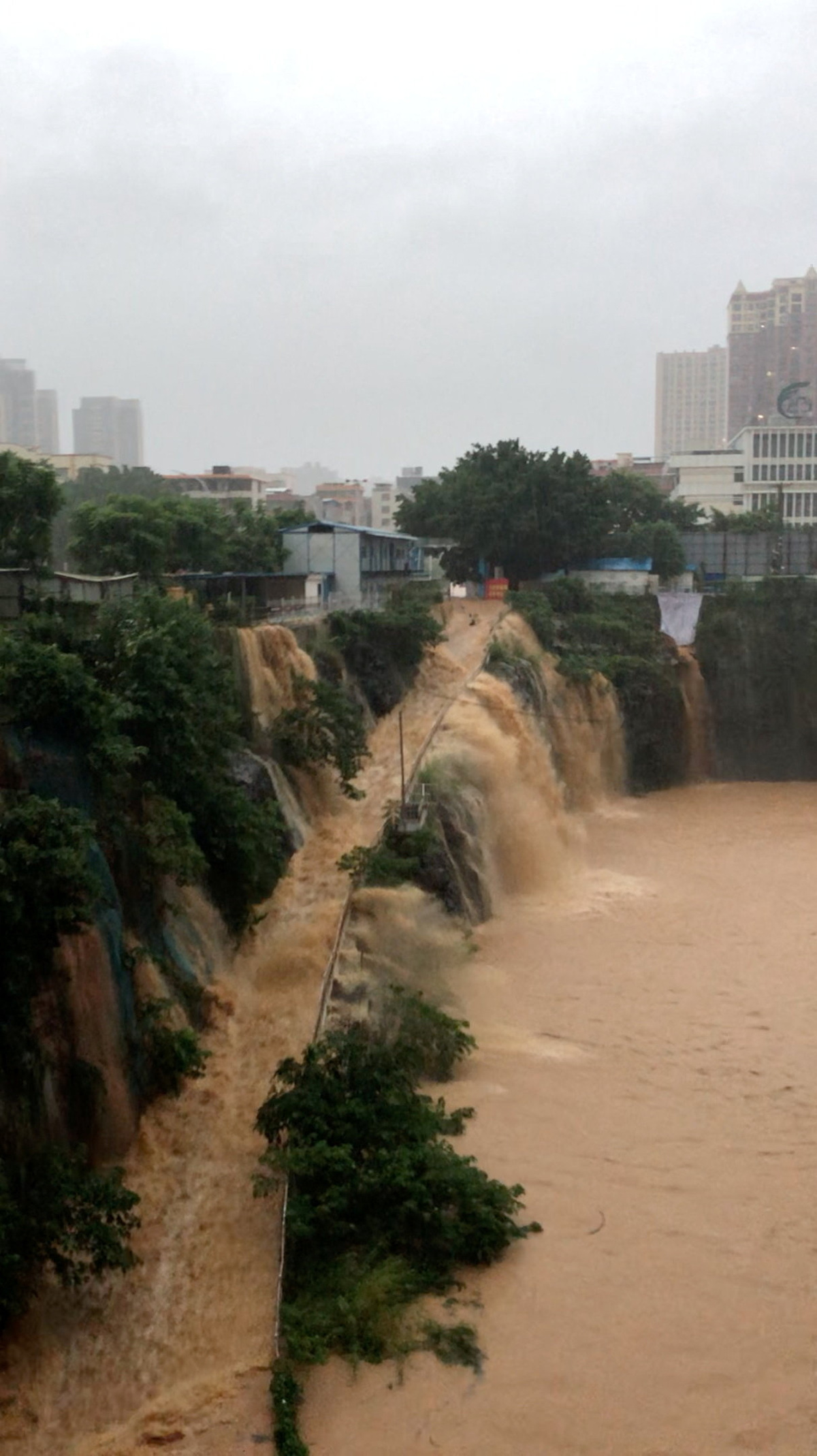 Floodwater flows down the side of a ramp at a construction site, amid heavy rain brought by Typhoon Maysak, in Guigang, Guangxi Zhuang Autonomous Region, China, in this still image obtained from social media video.  Social Media/via REUTERS